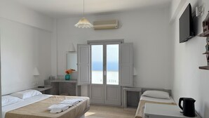 Une chambre d’hôtel moderne, équipée d’un lit, d’un bureau et offrant une vue sur la mer.