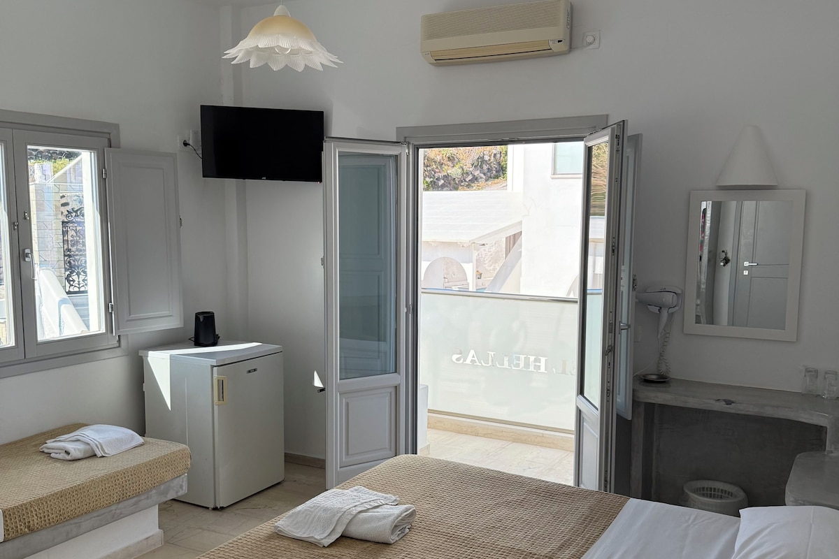 A hotel room with a bed, a desk, a television, and a bathroom.