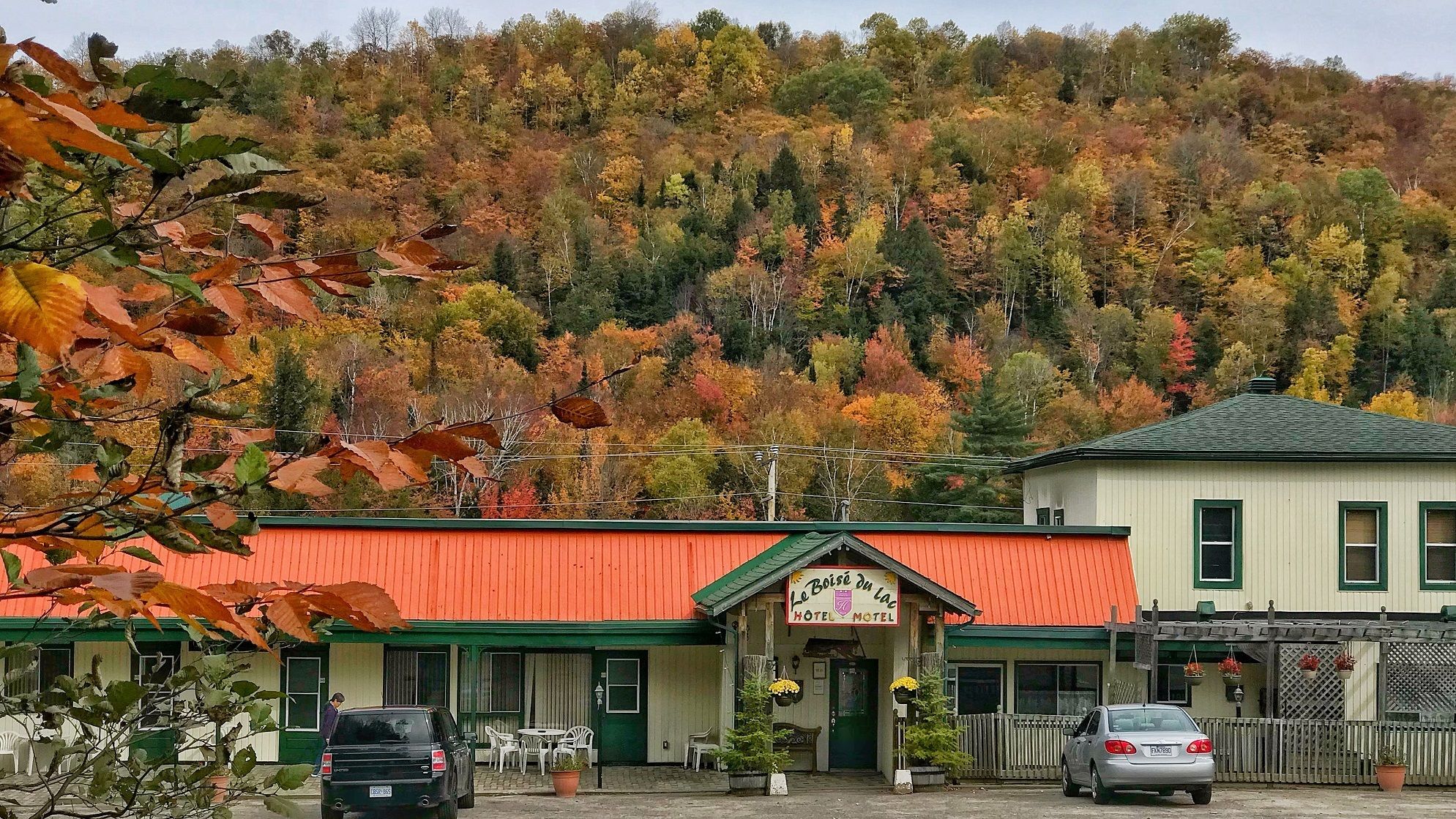 A hotel with a red roof and green trim, surrounded by autumn foliage.