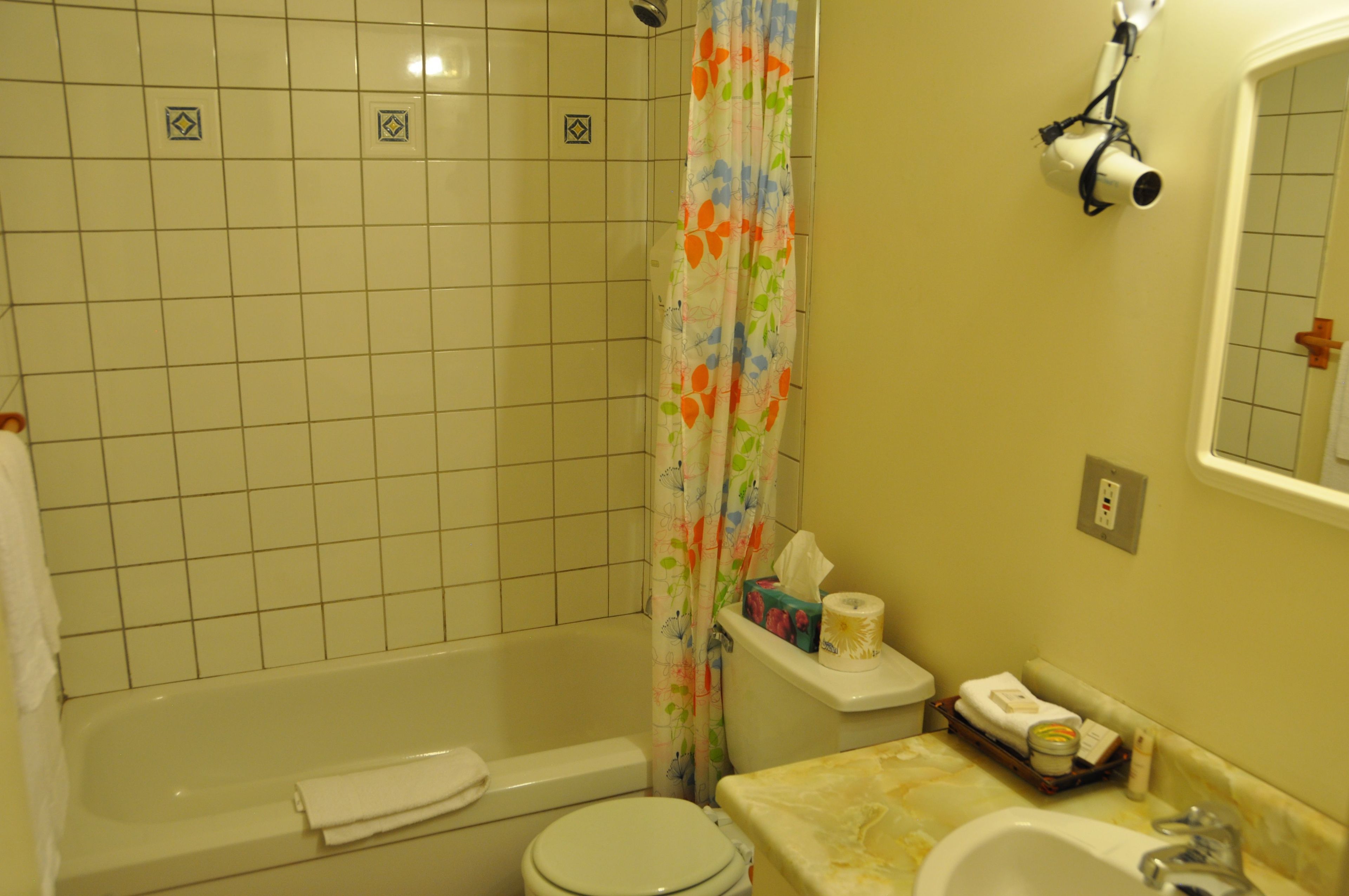 A bathroom with a bathtub, toilet, sink, and a shower curtain.