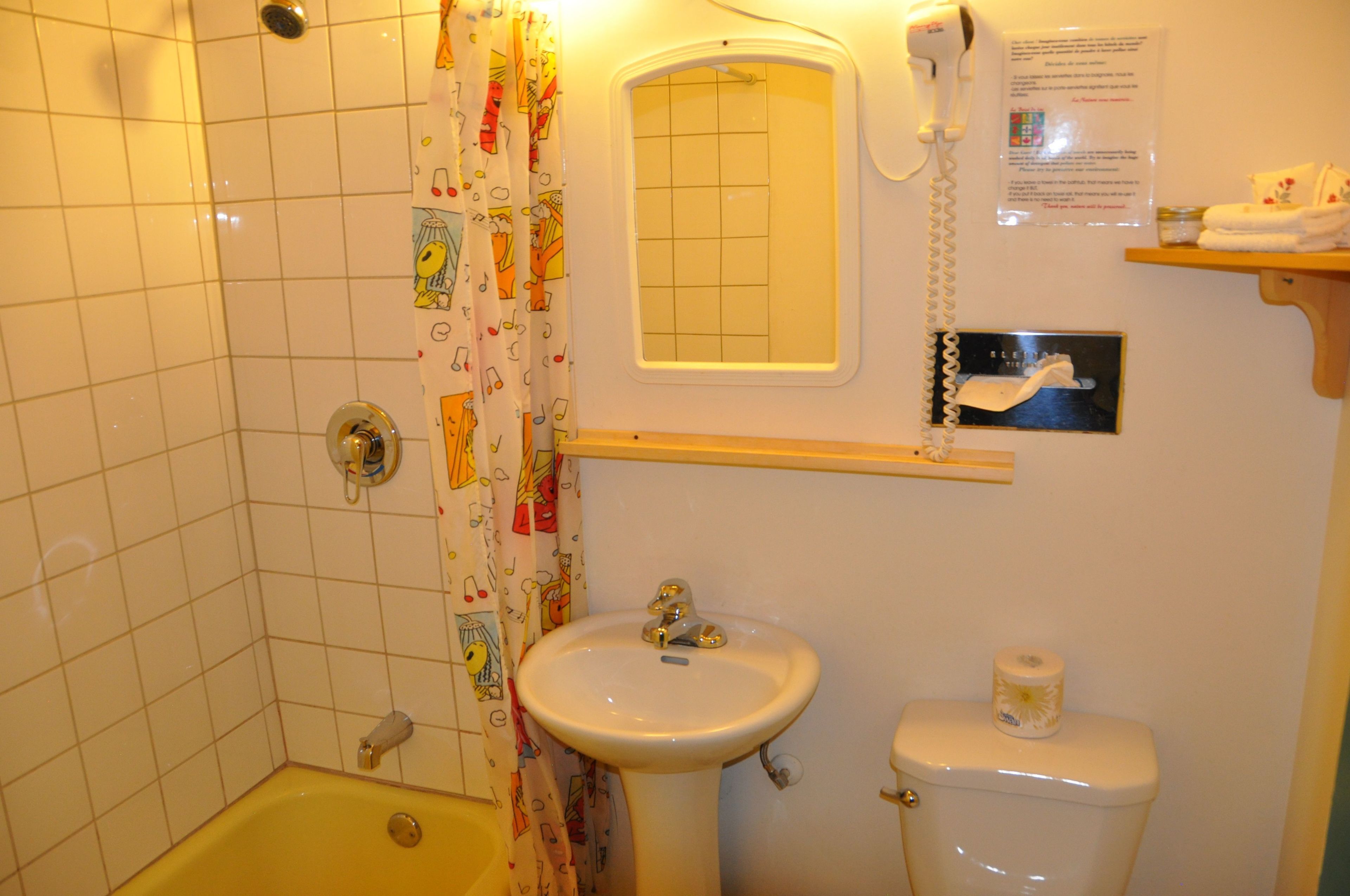 A bathroom with a bathtub, sink, toilet, and a shower curtain with a musical pattern.