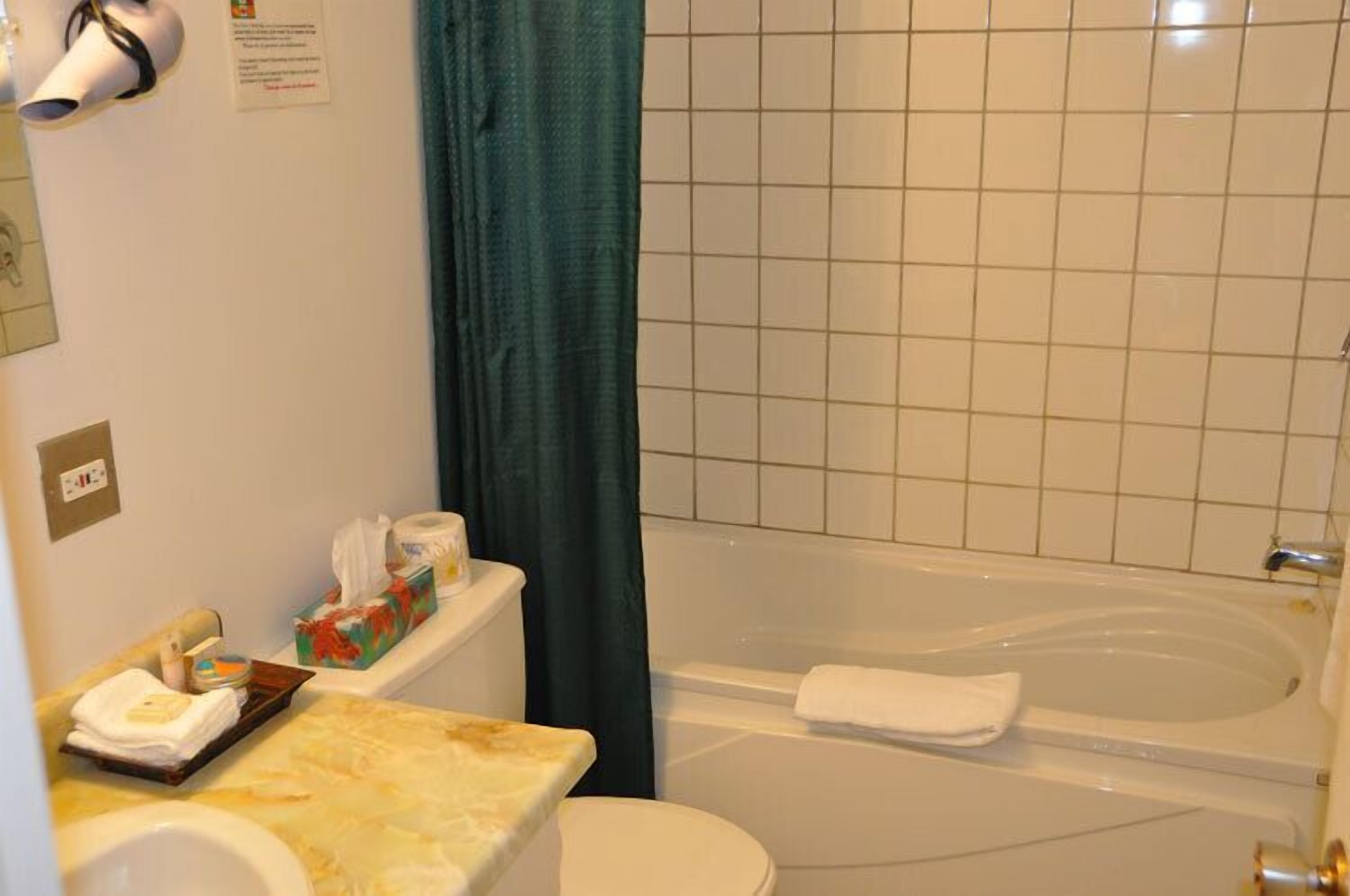 Un baño con inodoro, lavamanos y bañera. Hay toallas y artículos de tocador en la encimera.