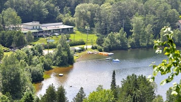 A lakeside property with a large building, boats, and dense forest.