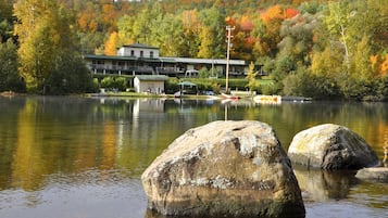 A lakeside lodge with a large building, docked boats, and a forested backdrop.