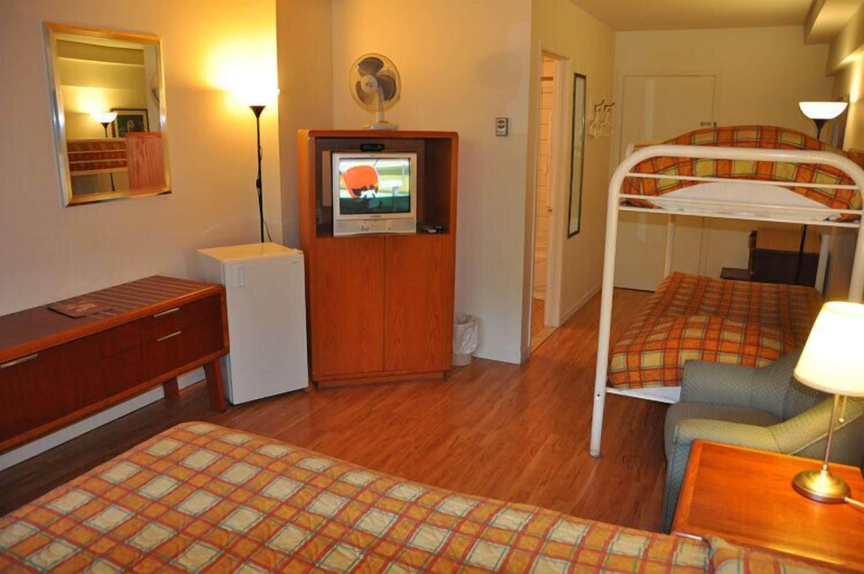 Hotellihuone, jossa on kerrossänky, pieni televisio, työpöytä ja yöpöytälamppu.