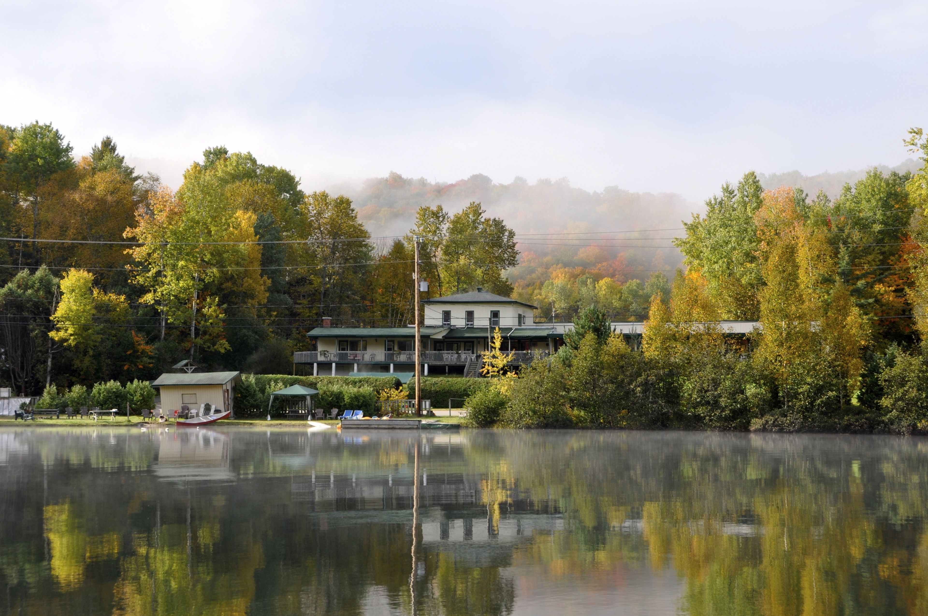 A lakeside view with a building featuring multiple balconies and a dock.