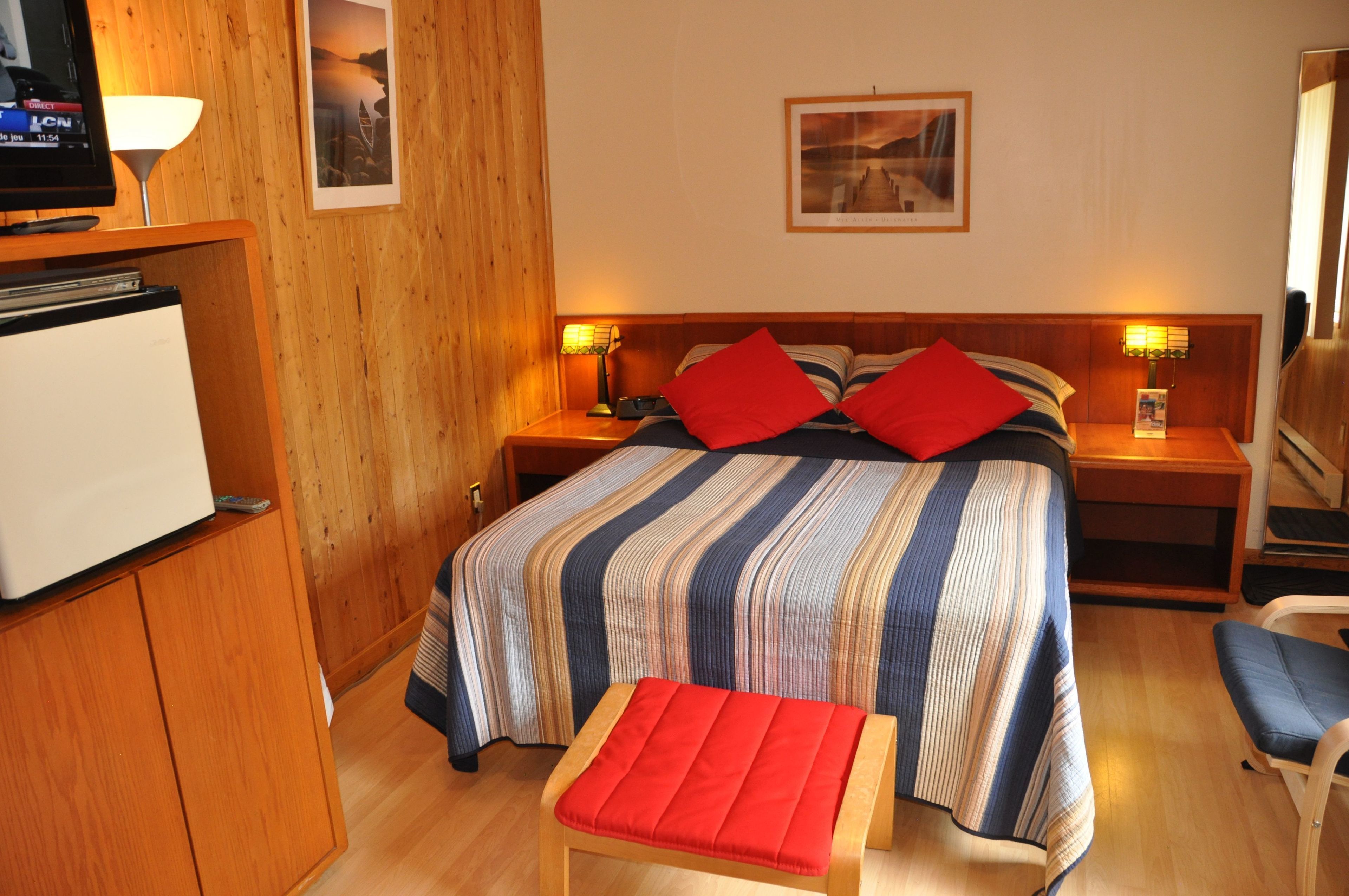 Une chambre d’hôtel comprenant un lit, deux tables de chevet, un téléviseur, un bureau et une chaise.