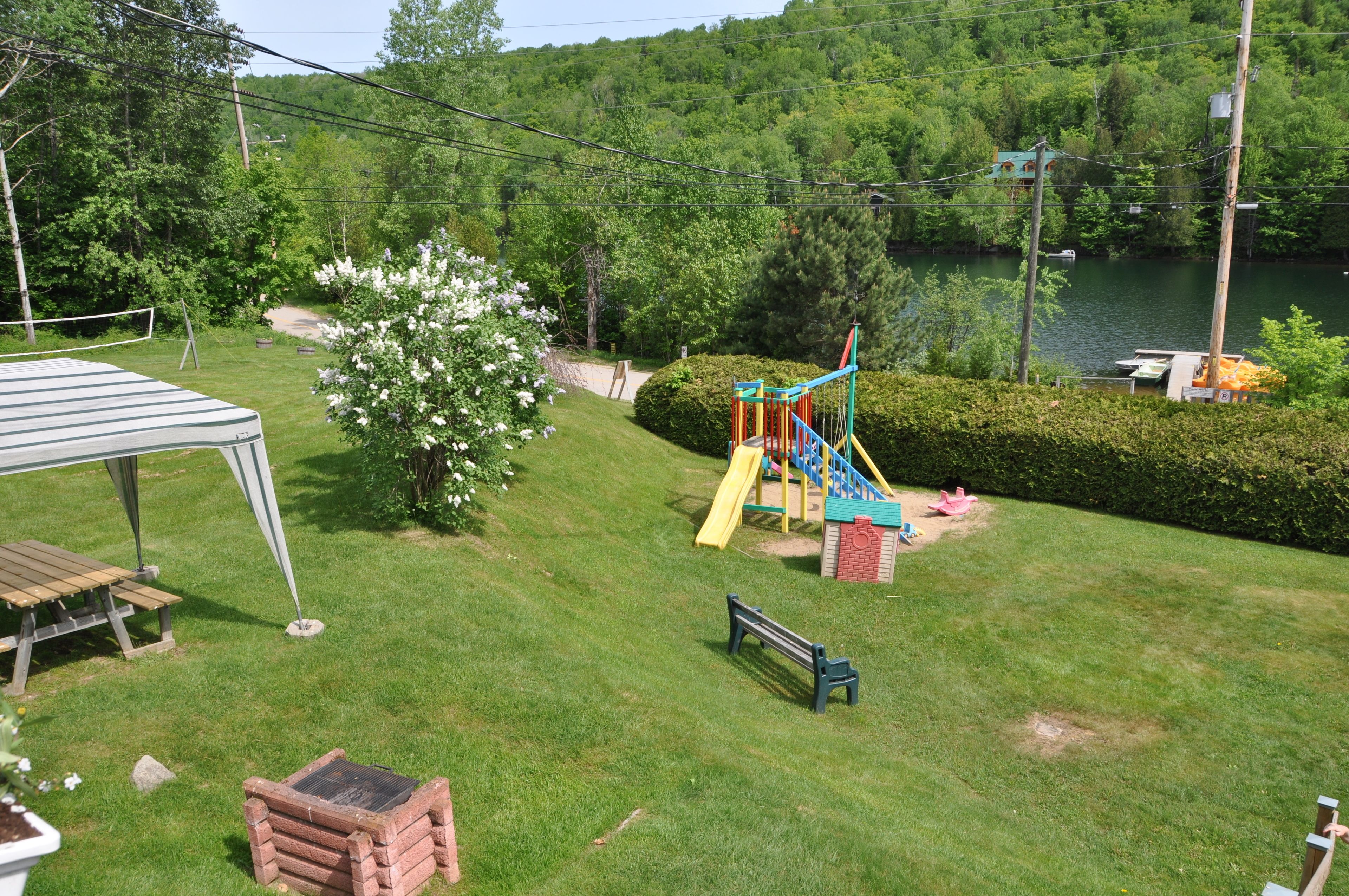 A grassy yard with a playground, a picnic table, and a wooden deck.
