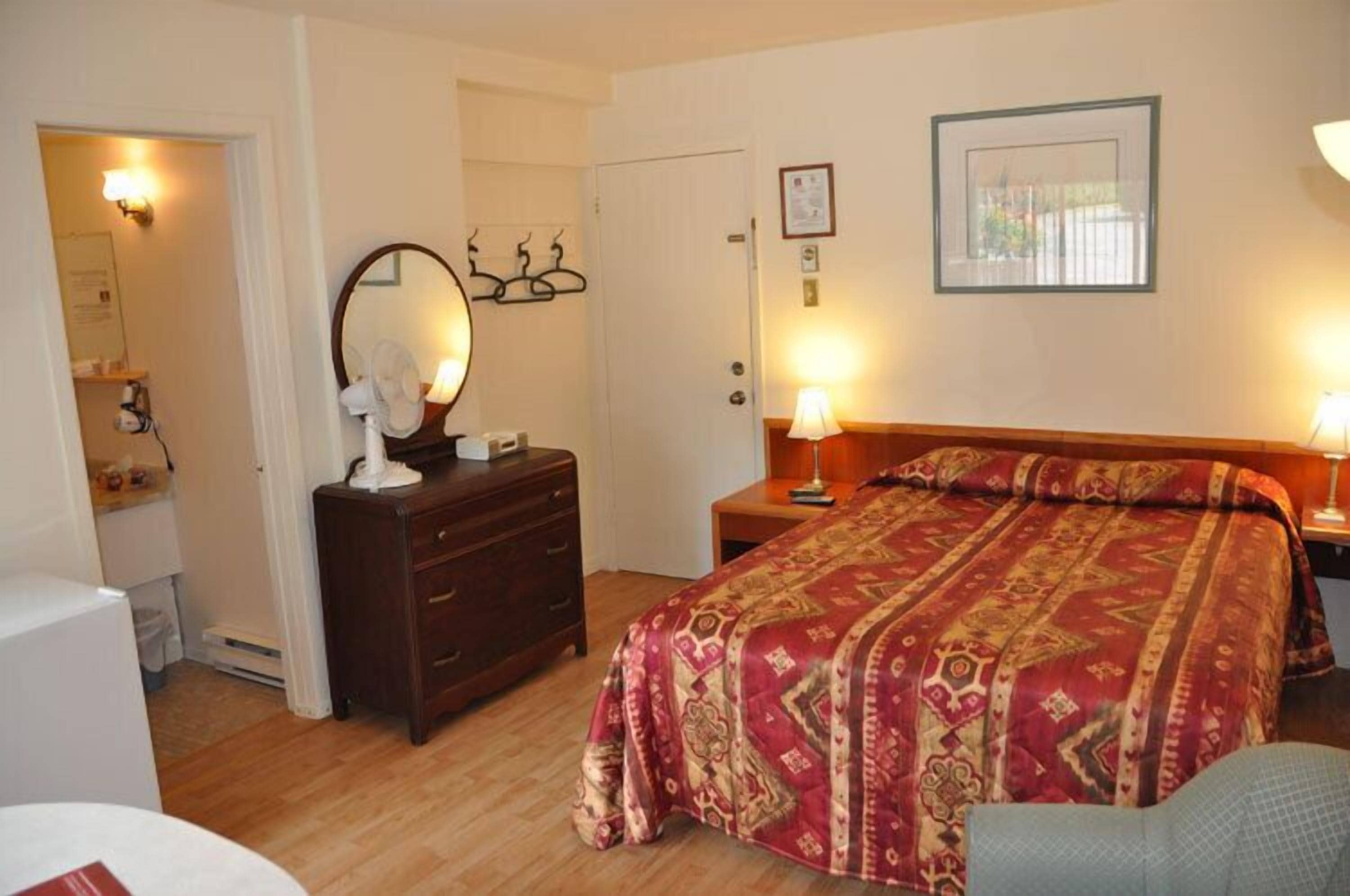 Een slaapkamer met een groot bed, een dressoir, een spiegel en twee bedlampen.