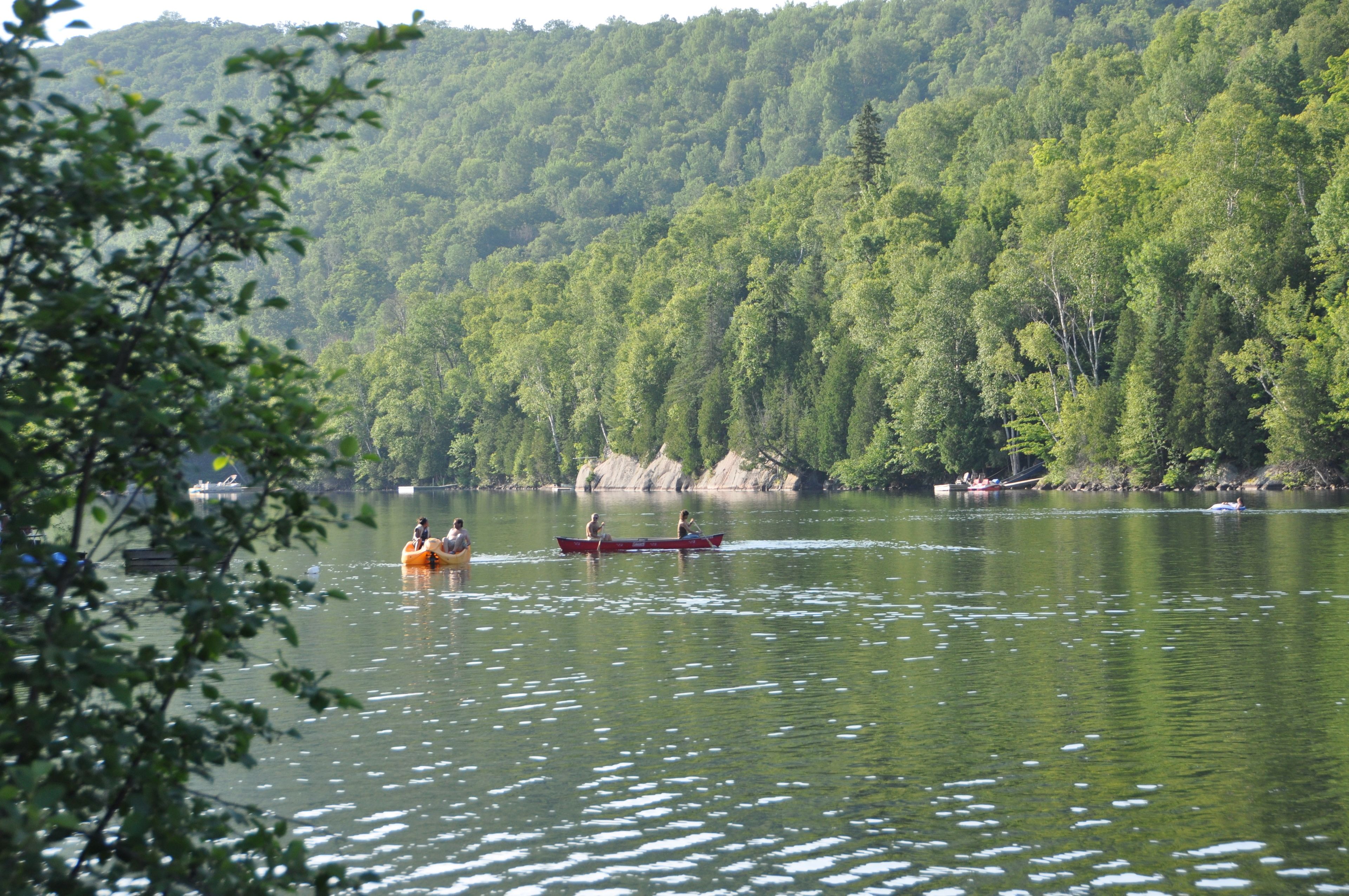 A calm lake with boats and a forested hillside in the background.