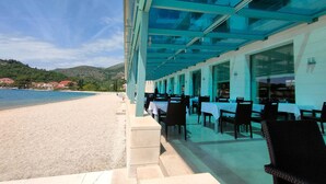 Un restaurant en bord de mer avec une terrasse offrant une vue sur la plage.