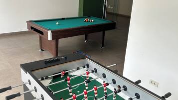 A room with a foosball table and a pool table.