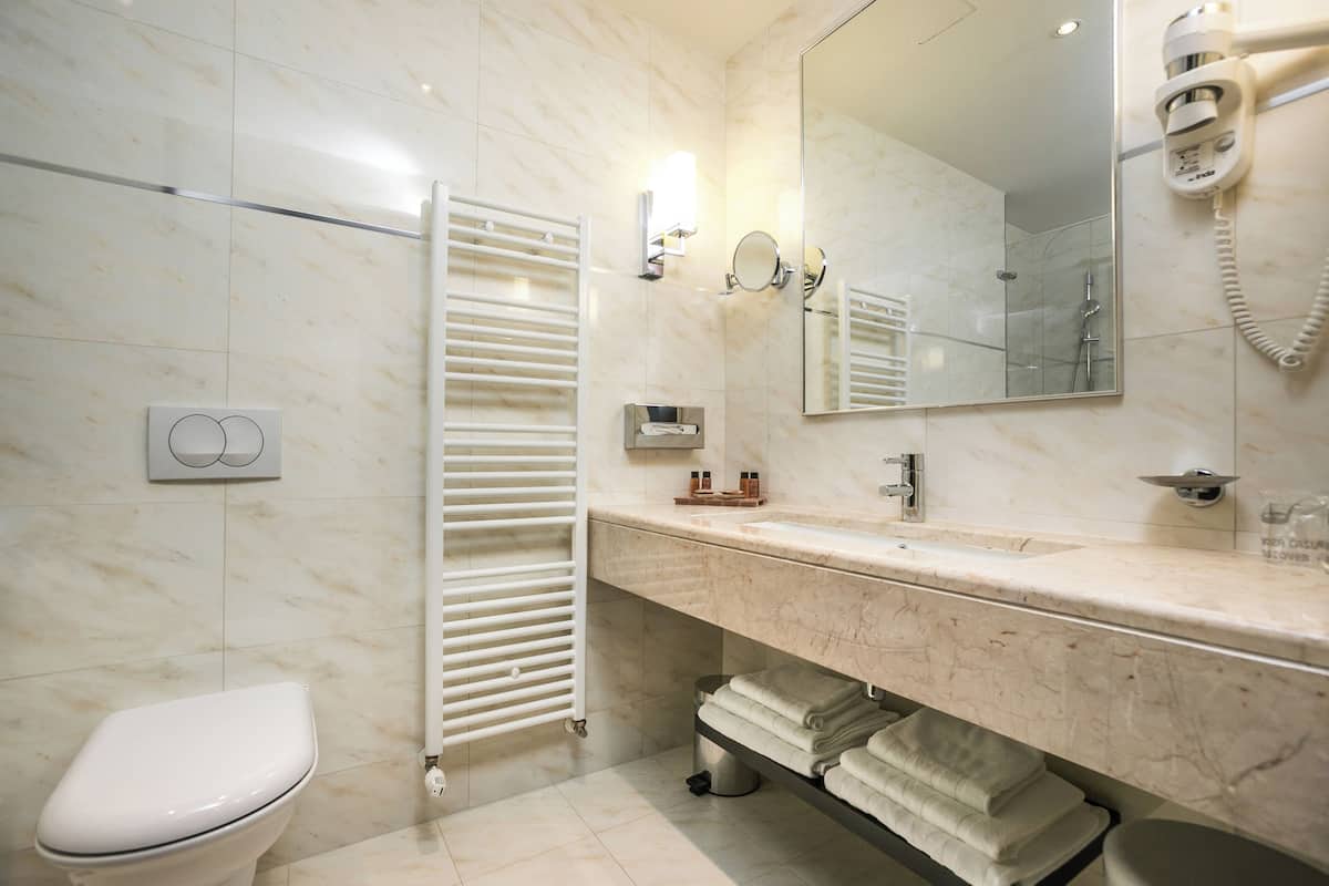 Une salle de bain moderne avec des toilettes blanches, une douche en verre, un lavabo en marbre et un porte-serviettes.