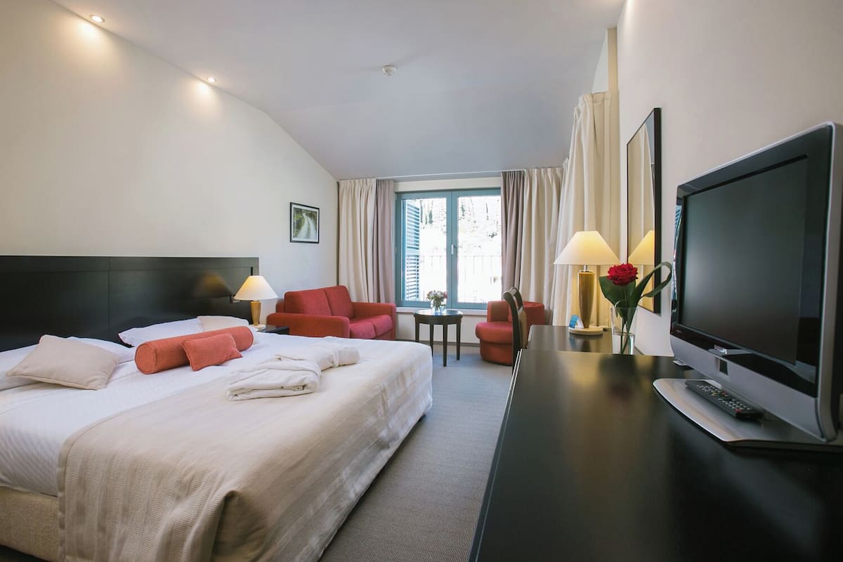 Une chambre d’hôtel avec un grand lit, une télévision, un bureau et deux chaises.