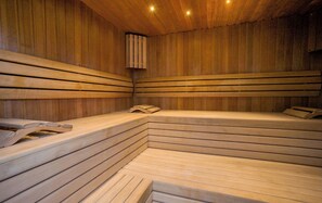 Un sauna avec des bancs en bois et un banc muni d’une serviette.