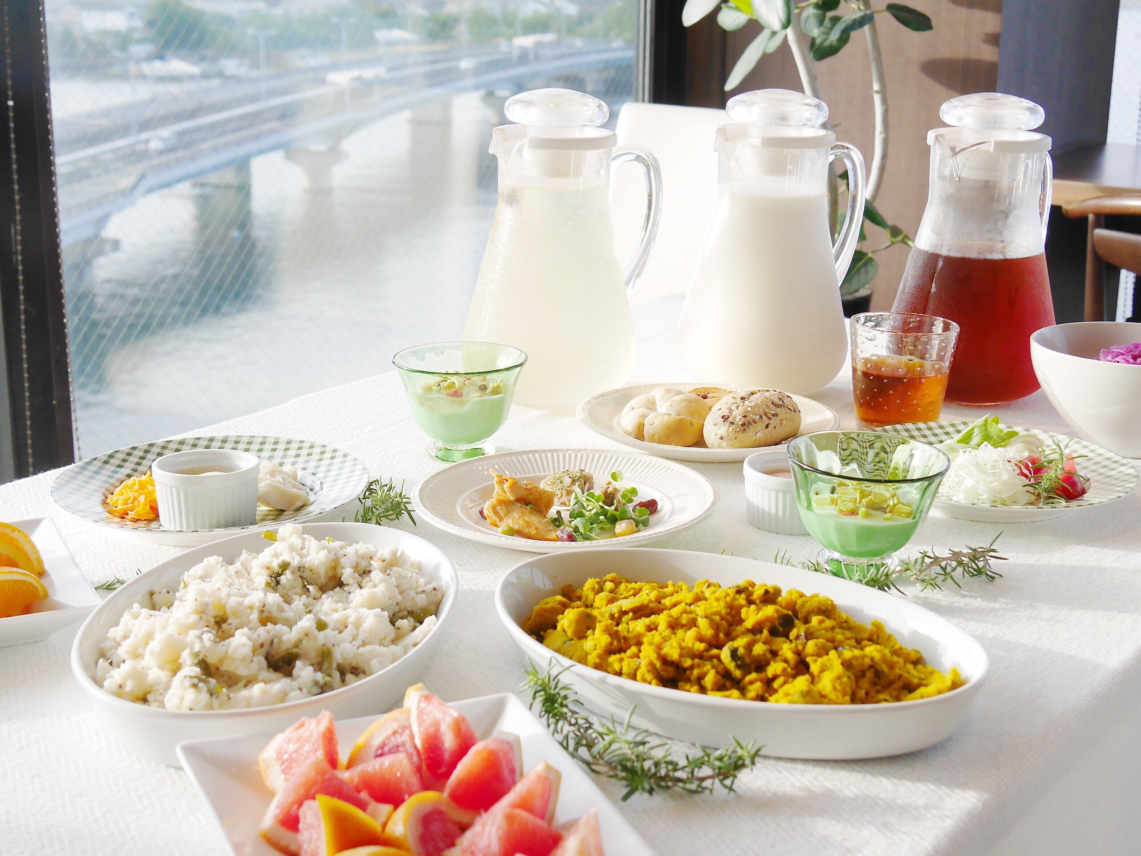 Une table dressée avec différents plats, notamment une carafe de lait, un verre de thé et des assiettes de nourriture.