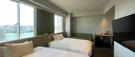 Habitación de hotel con dos camas, un escritorio, una televisión y vistas a la ciudad.