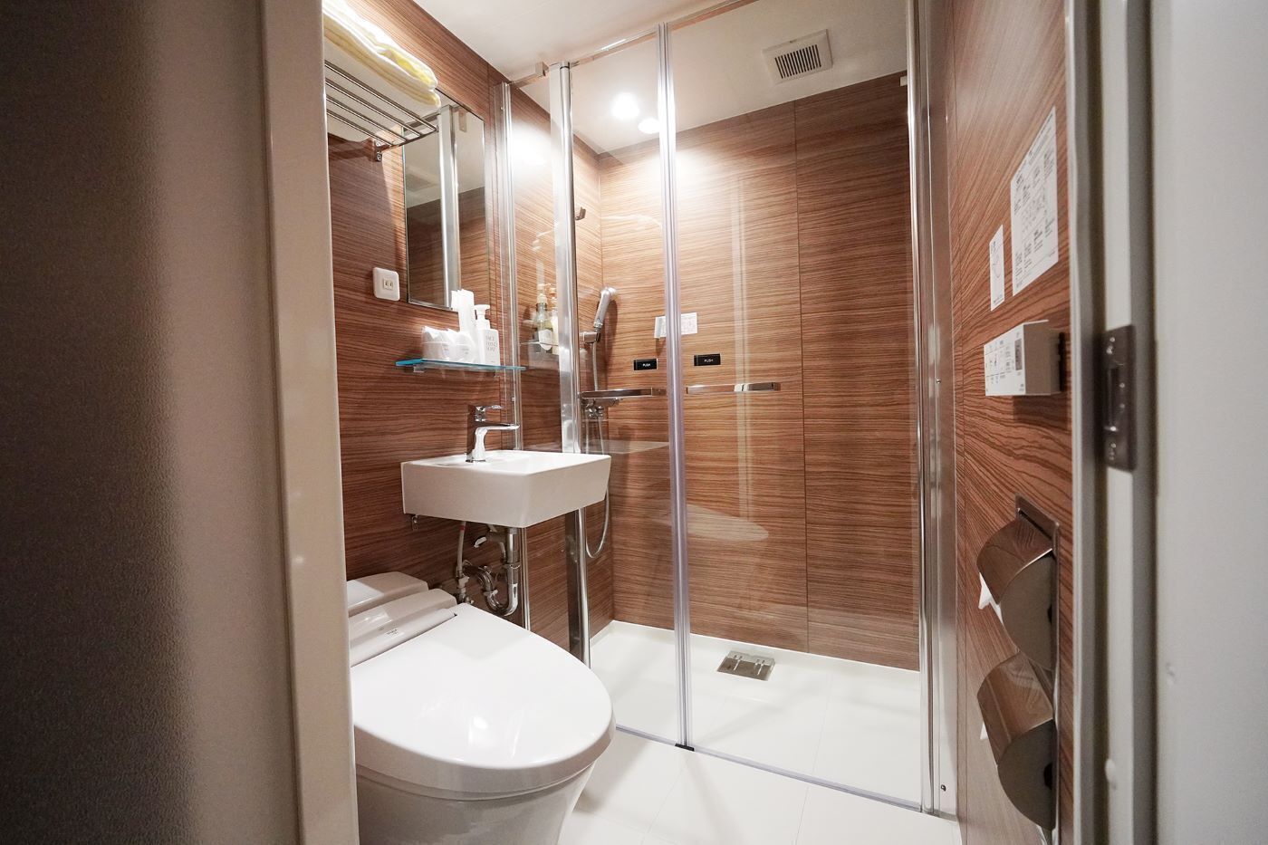 A modern bathroom with a glass shower enclosure, a white sink, and a toilet.