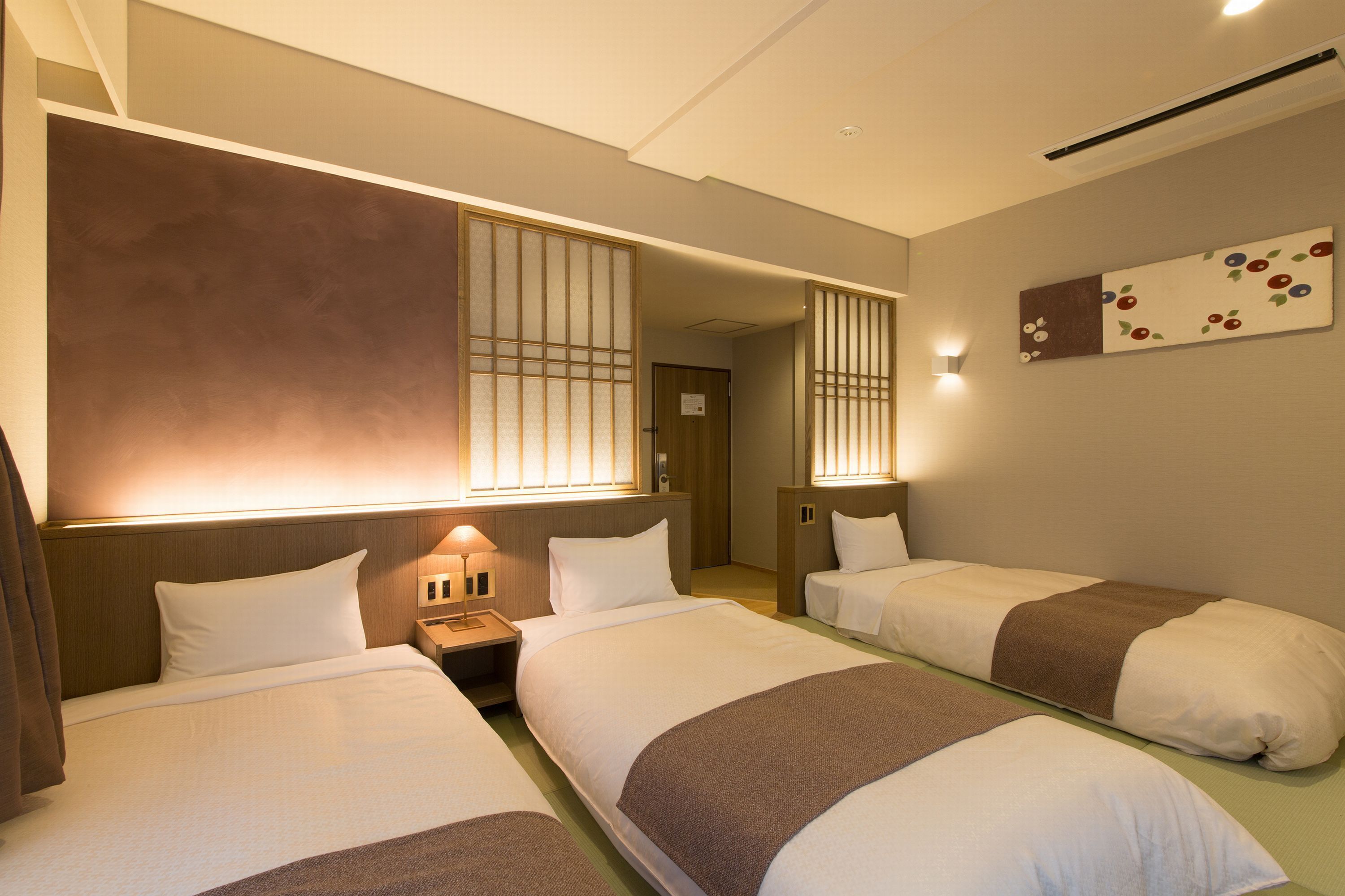 A hotel room with two beds, a nightstand, a wall-mounted lamp, and a decorative panel.