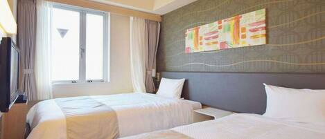 A hotel room with two beds, a large window with curtains, a flat-screen TV, and a wall with a colorful abstract painting.