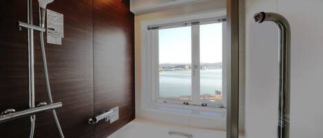 Un baño con bañera, ducha y ventana con vista al agua.