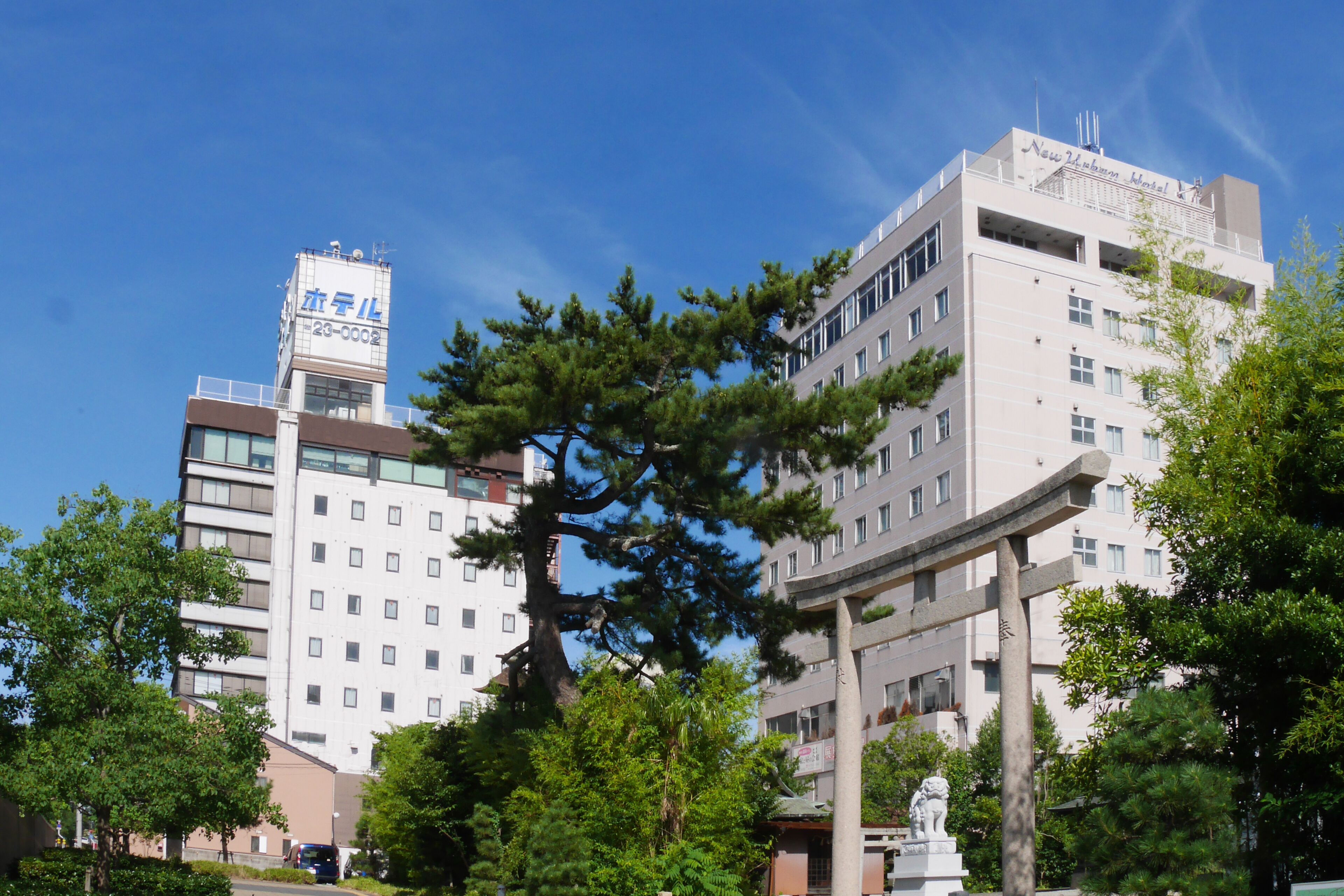 A multi-story building with a signboard, surrounded by trees and greenery.