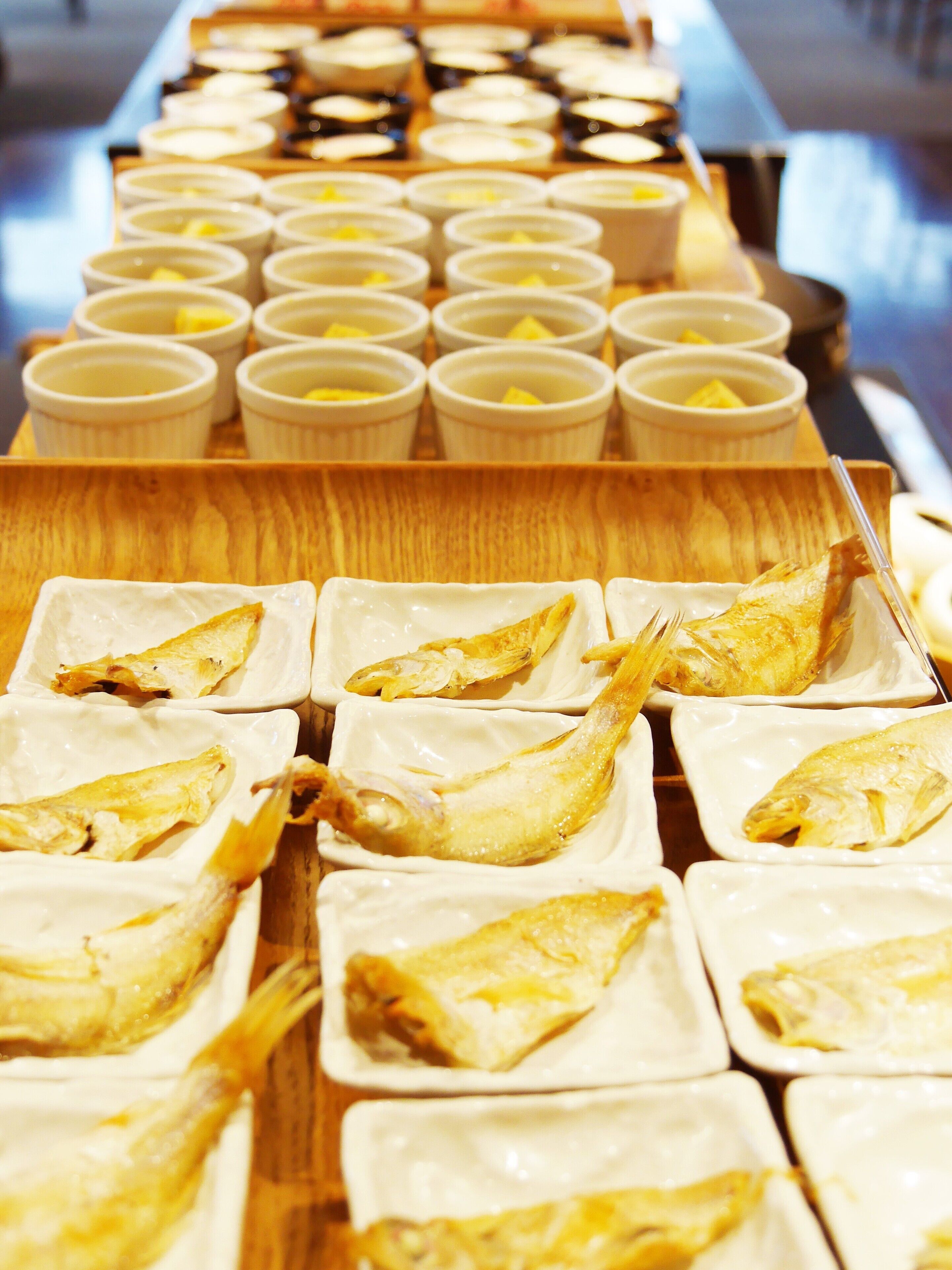 A buffet with various dishes including fish and small bowls of soup.
