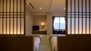 Habitación de hotel con dos camas, un escritorio con computadora, televisor y ventana con vistas.
