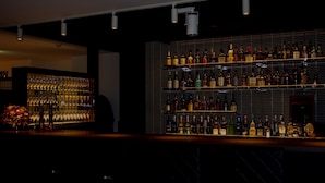 A bar area with shelves of liquor bottles, a bar counter, and a decorative light fixture. - Hotel Asia Center of Japan (Tokyo)