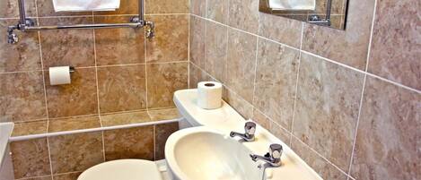 Un baño con inodoro, lavamanos y perchero para toallas.