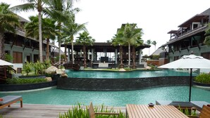 A pool area with wooden deck seating, palm trees, and a gazebo. - Mai Samui Beach Resort & Spa (Koh Samui)