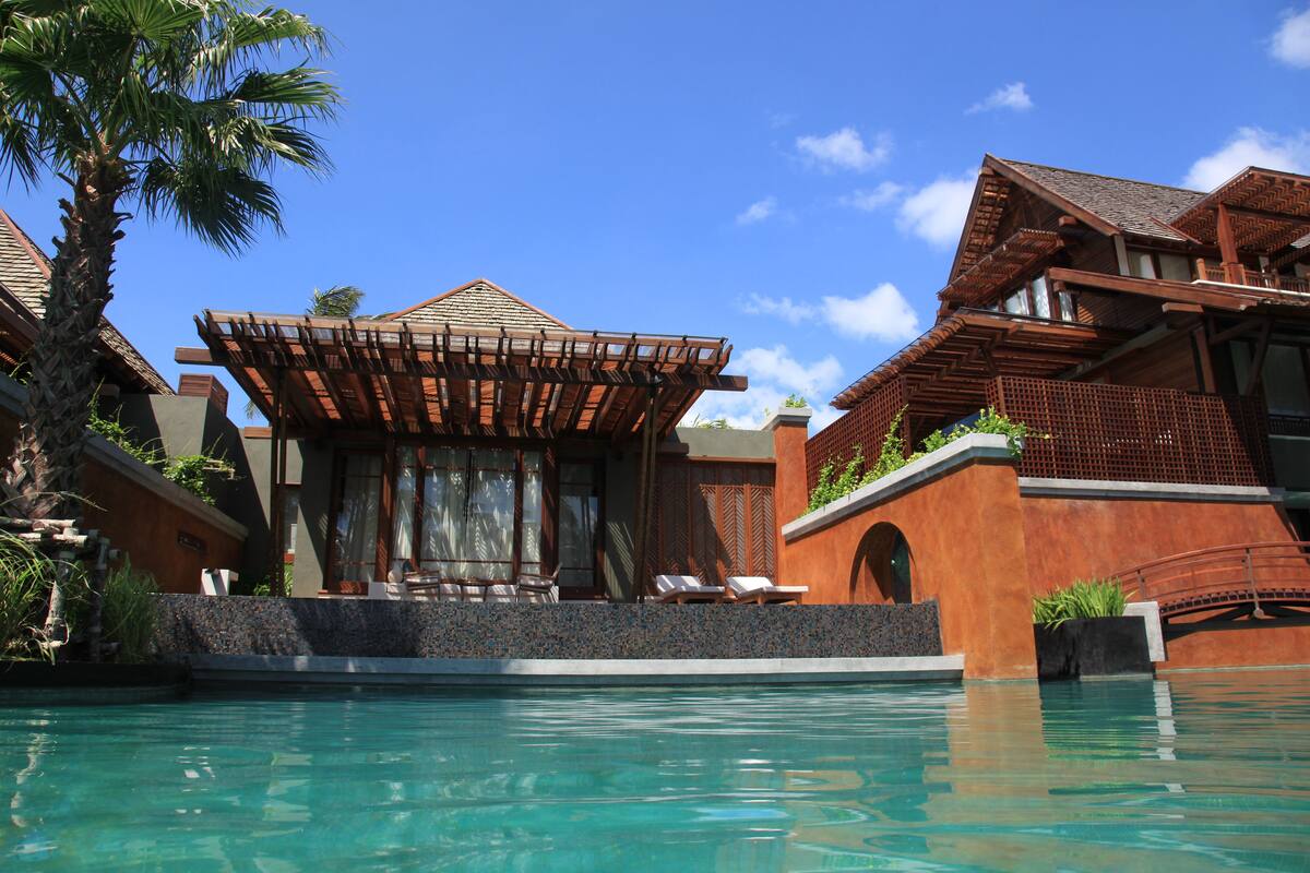 A resort with a pool, wooden pergolas, and a tropical setting.