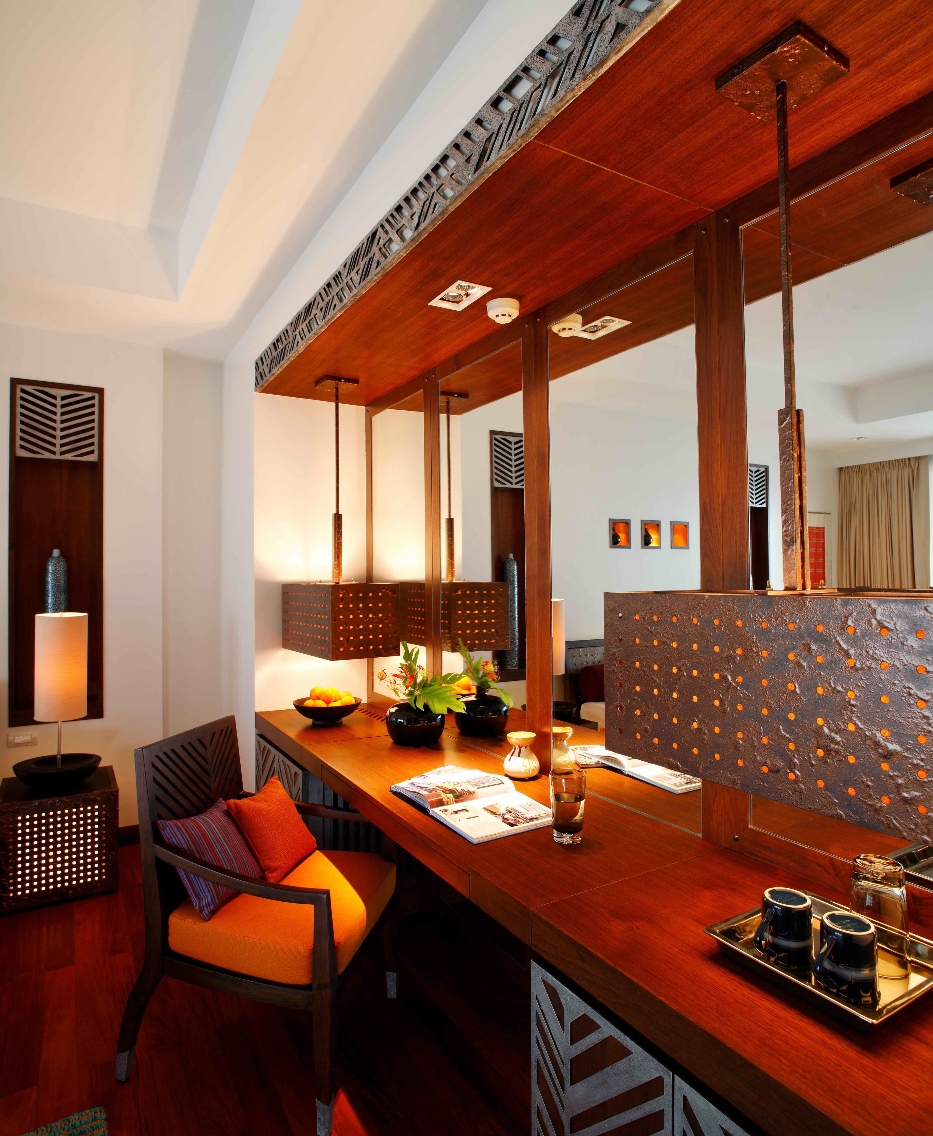 A modern hotel room with a wooden dining table, a sofa, and a decorative partition.