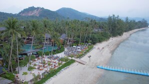 Un complexe hôtelier doté d’une piscine, d’une plage et de palmiers.