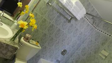 A bathroom with a toilet, sink, and bathtub. There are towels and toiletries on the sink counter.