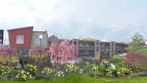 A hotel named Capri Inn with a modern architectural style, featuring a prominent entrance and a well-maintained garden with various flowers. - Capri Inn (St. Catharines)