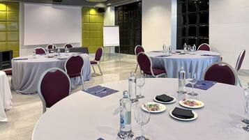 A conference room with round tables, chairs, and a presentation screen.