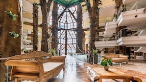 A spacious atrium with high ceilings, wooden benches, and potted plants. - Holiday World Polynesia Affiliated by Melia (Benalmádena)