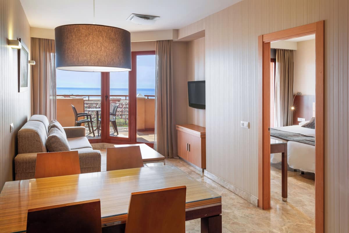 Een hotelkamer met een zithoek, een bank, een televisie en een balkon met uitzicht.