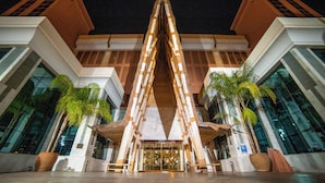 A modern building with a central atrium, large glass windows, and palm trees. - Holiday World Polynesia Affiliated by Melia (Benalmádena)