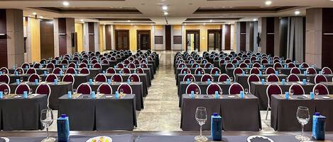 A conference room with rows of tables, chairs, and water bottles.