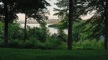 A forested area with a lake and a house in the background.