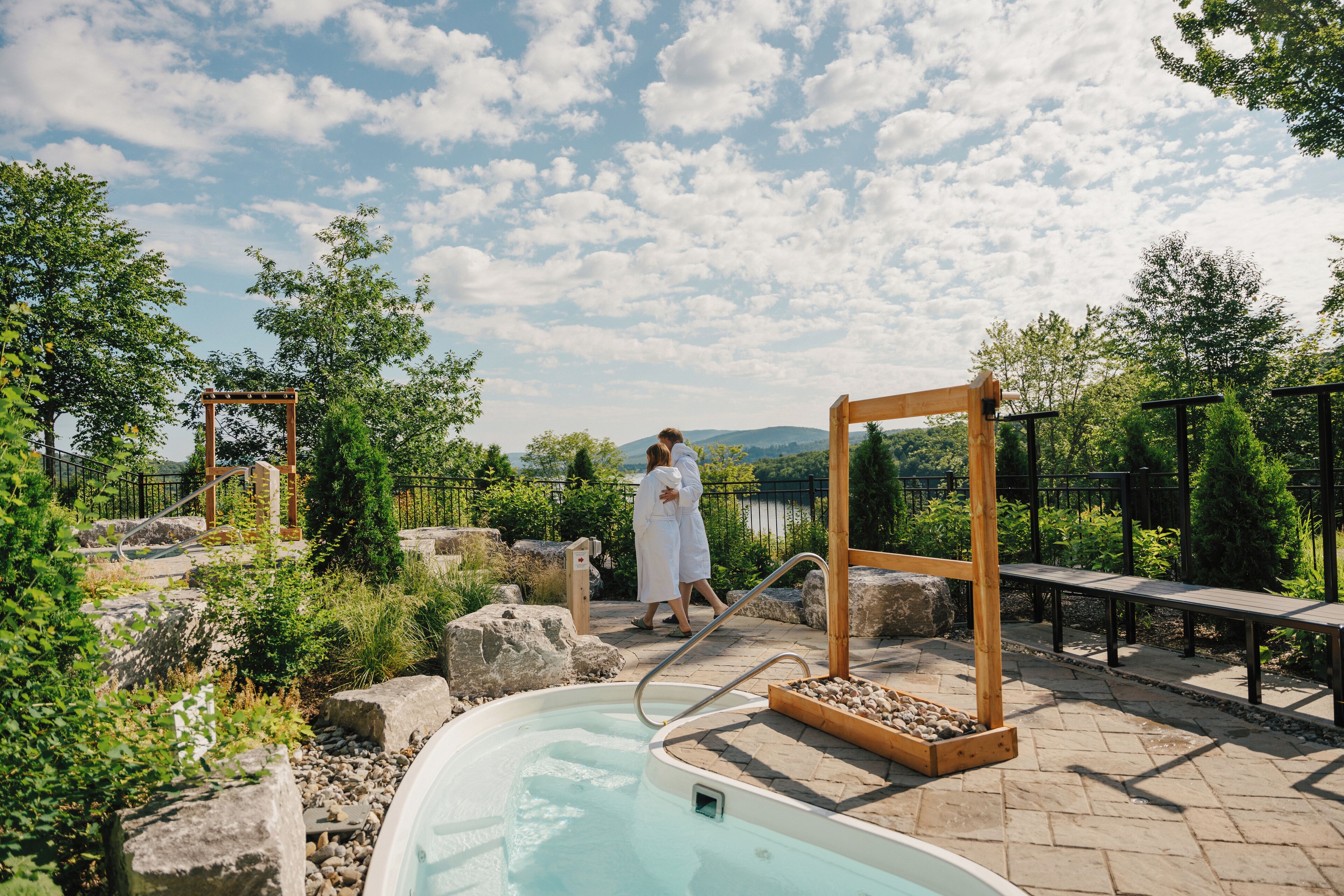Piscina exterior con cubierta de madera, rodeada de vegetación y vistas panorámicas.