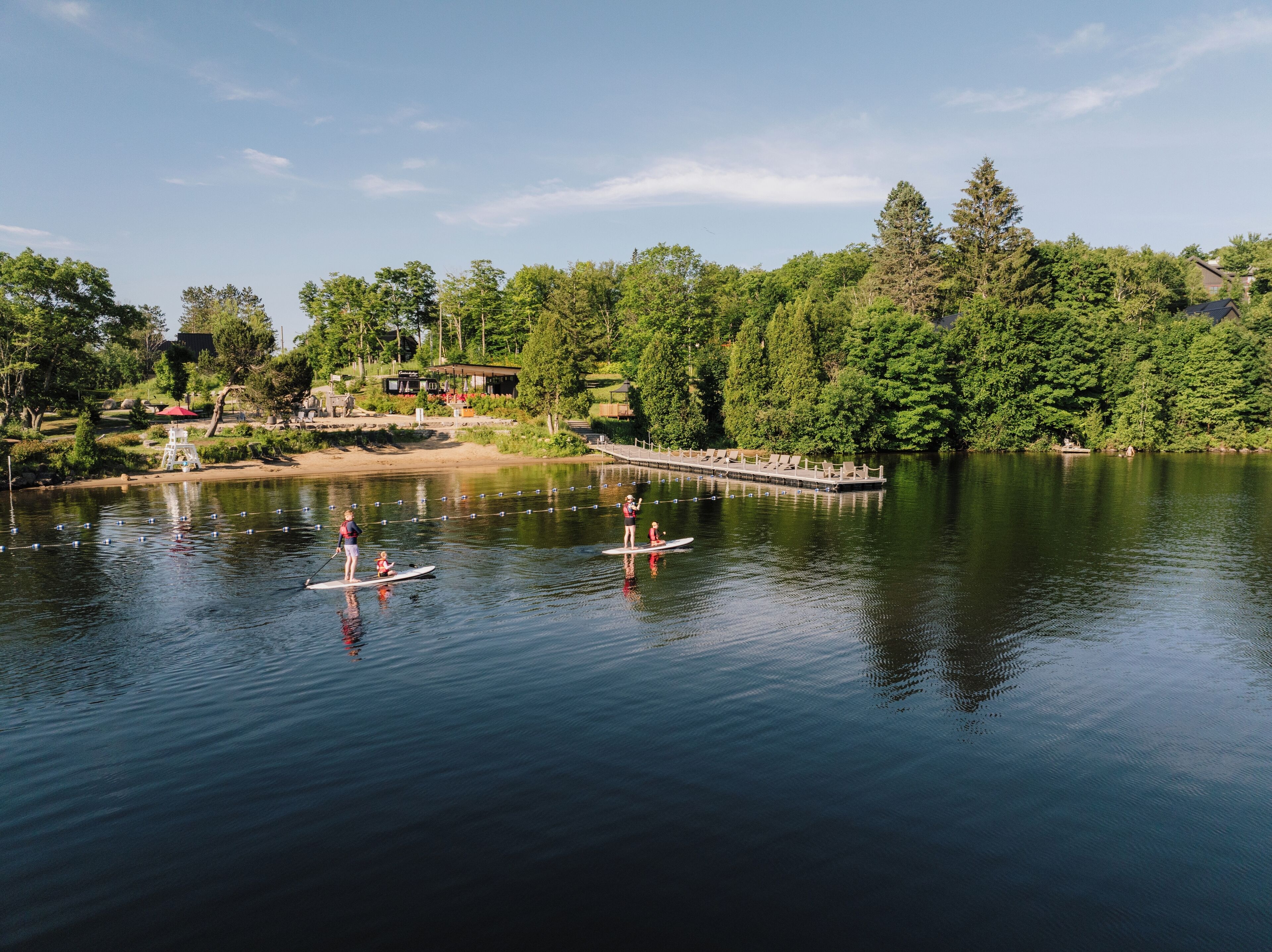 Un lac paisible où l’on peut faire du paddle, avec un quai et un bâtiment doté d’une terrasse.