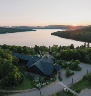 A lakeside lodge with a large building featuring a steep roof, surrounded by dense forest and a calm lake. - Duchesnay - SEPAQ (Sainte-Catherine-de-la-Jacques-Cartier)