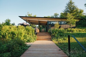 A modern building with a wooden deck leading to a covered entrance. - Duchesnay - SEPAQ (Sainte-Catherine-de-la-Jacques-Cartier)