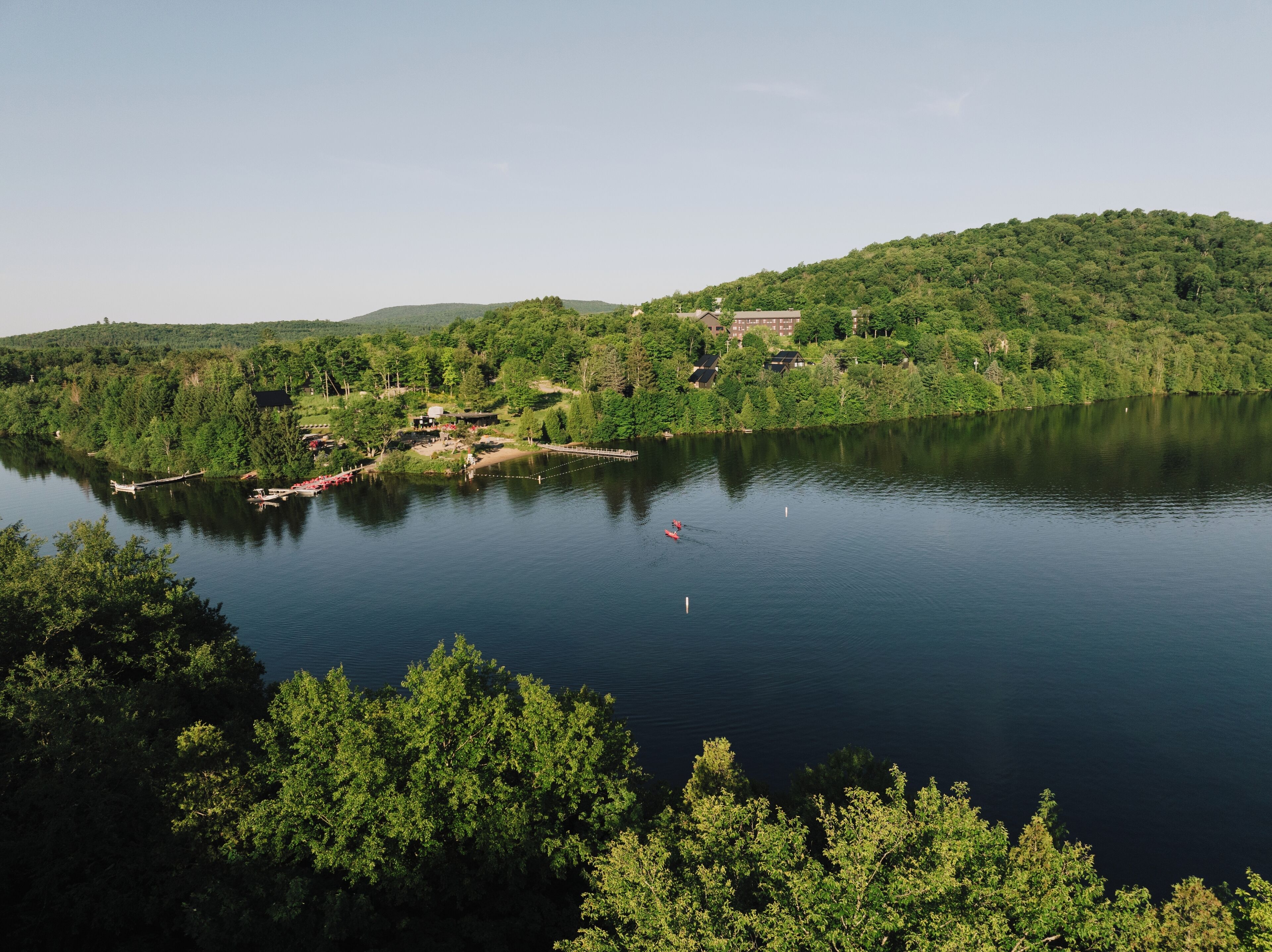Un cadre paisible au bord d’un lac, avec un petit quai et un bâtiment entouré d’une végétation luxuriante.