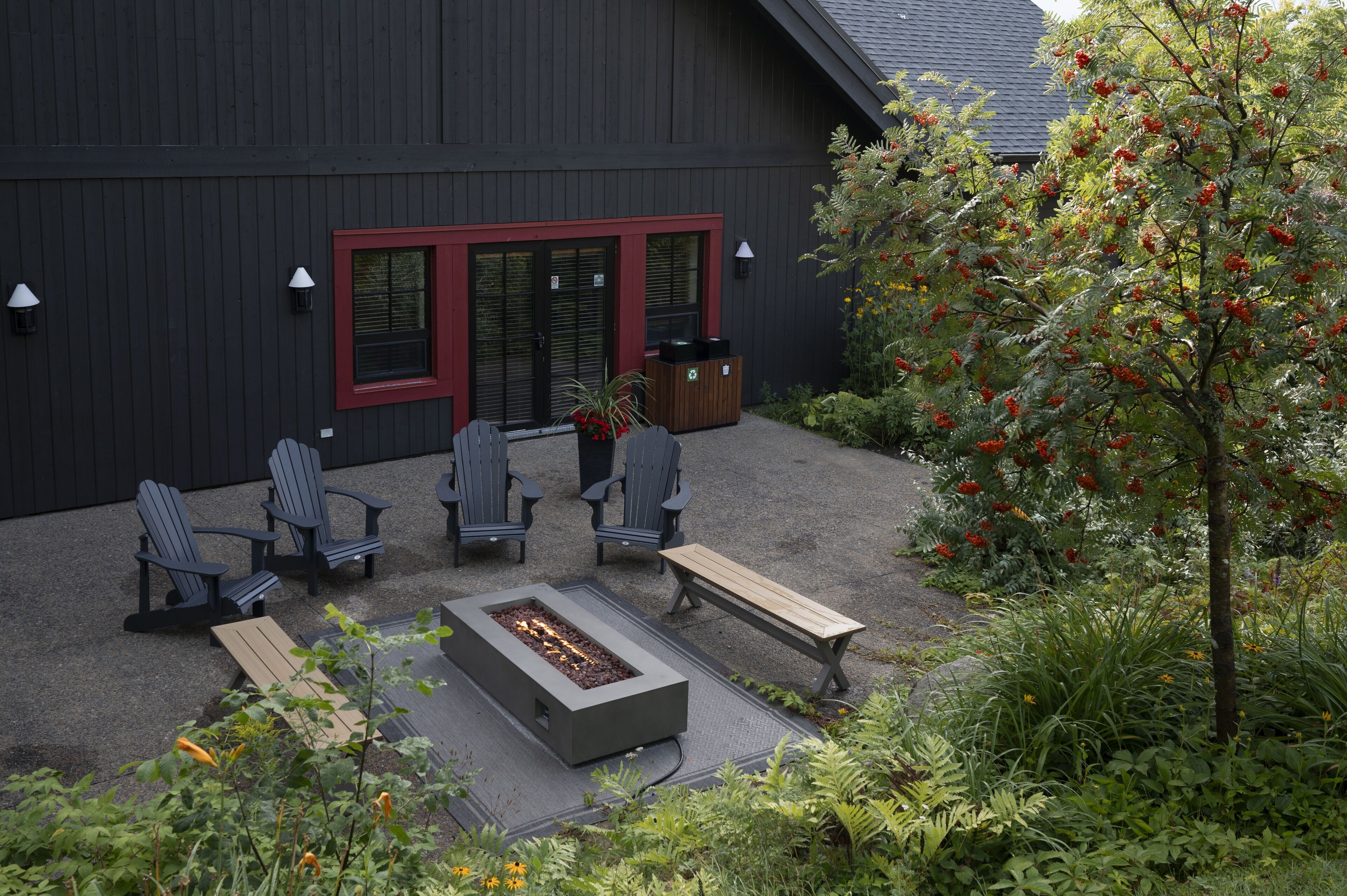 A patio with Adirondack chairs, a fire pit, and a wooden bench.