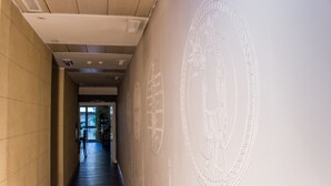 A hallway with a large wall mural, a wooden ceiling, and a door at the end. - Hotel Patavium (Padova)