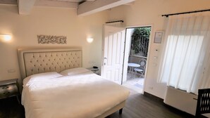 A bedroom with a large bed, a nightstand, a chair, and a door leading to a balcony. - Hotel Patavium (Padova)